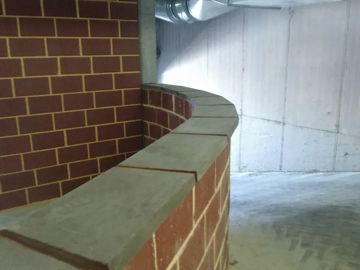 New coping stones laid to a curved brick wall